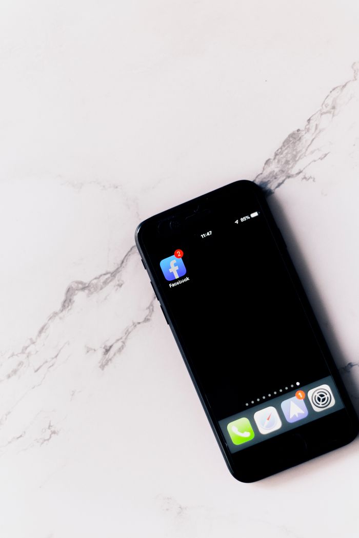 project-03-b Close-up of a smartphone showing a Facebook app notification on a marble surface.